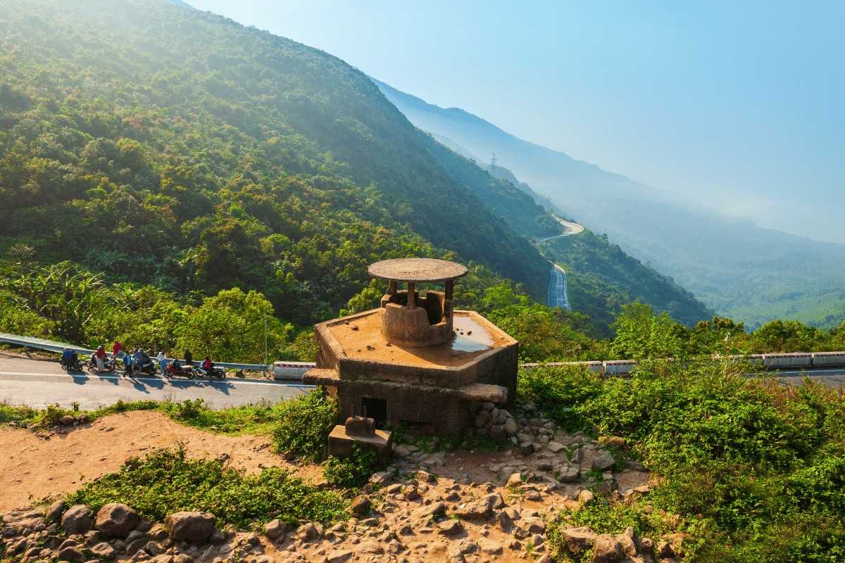Hai Van Pass French bunker viewpoint sunrise motorbike tour Hai Van Pass French bunker stands by the roadside as early morning sun lights up the mountains and travelers rest.