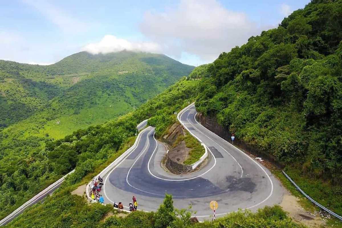 Hai Van Pass iconic hairpin turn scenic viewpoint Hai Van Pass features its iconic sharp hairpin turn surrounded by vibrant green forests and resting travelers.