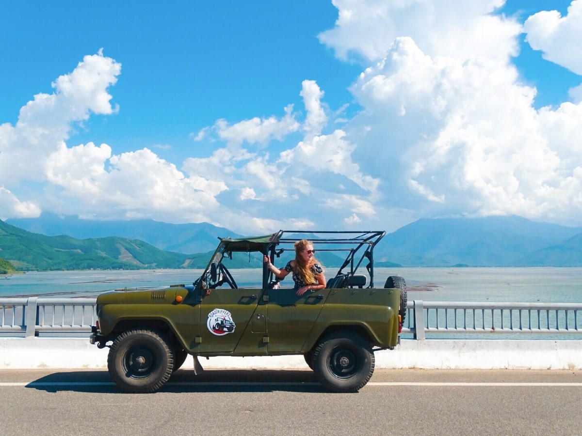 Tourist enjoying a jeep adventure along the Hai Van Pass, with a scenic mountainous backdrop