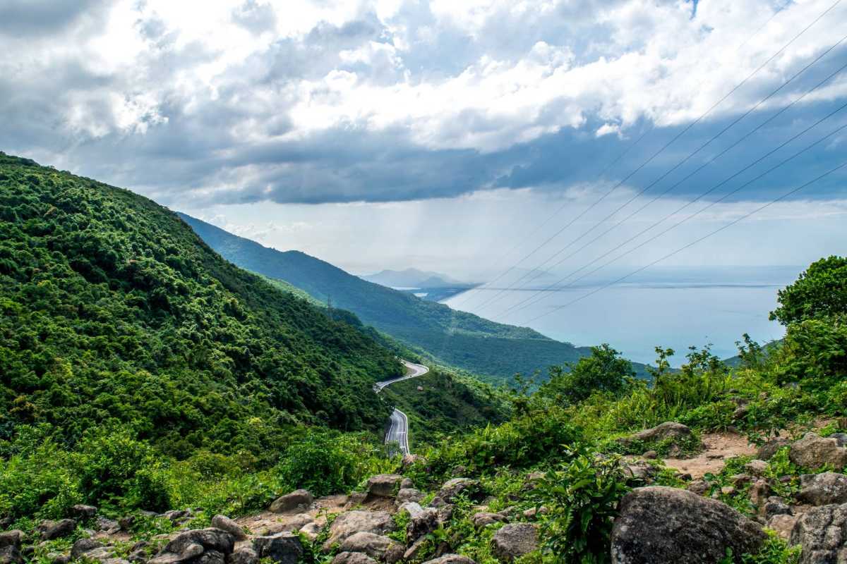 Hai Van Pass lush mountains dramatic coastal highway Hai Van Pass winds through lush green mountains above a curving highway and central Vietnam’s dramatic coastline.