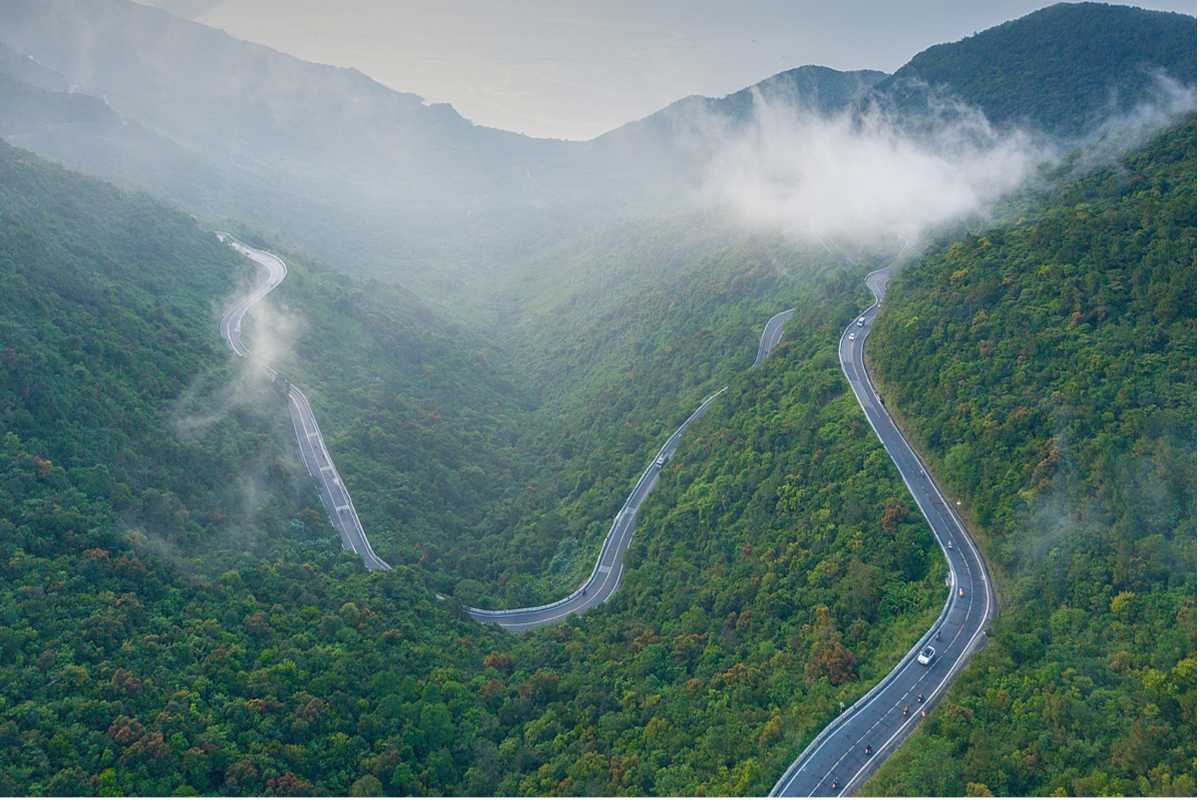 Hai Van Pass misty mountains and winding highway panorama Hai Van Pass reveals misty green mountains and a winding highway weaving through lush central Vietnam hills.