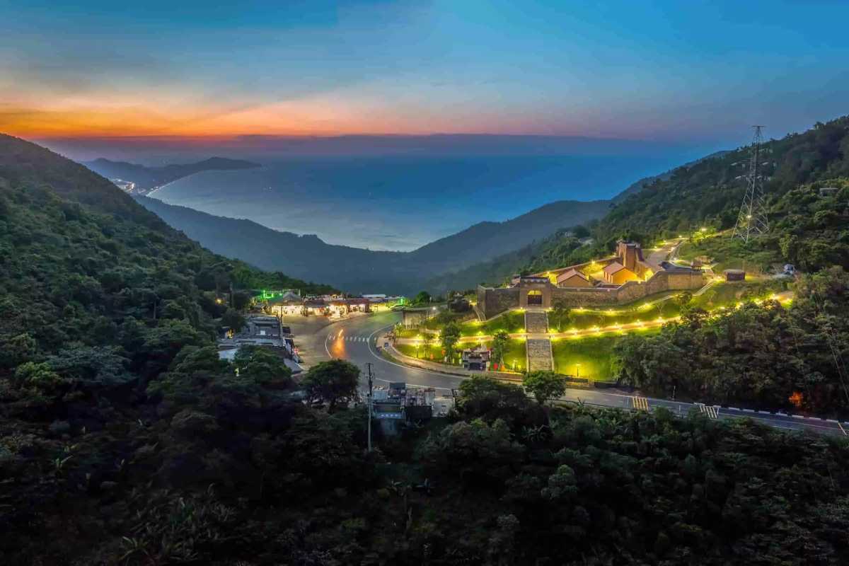 Hai Van Pass night view illuminated fortress and valley Hai Van Pass at night displays a brightly illuminated fortress with winding mountain roads and distant sea views.