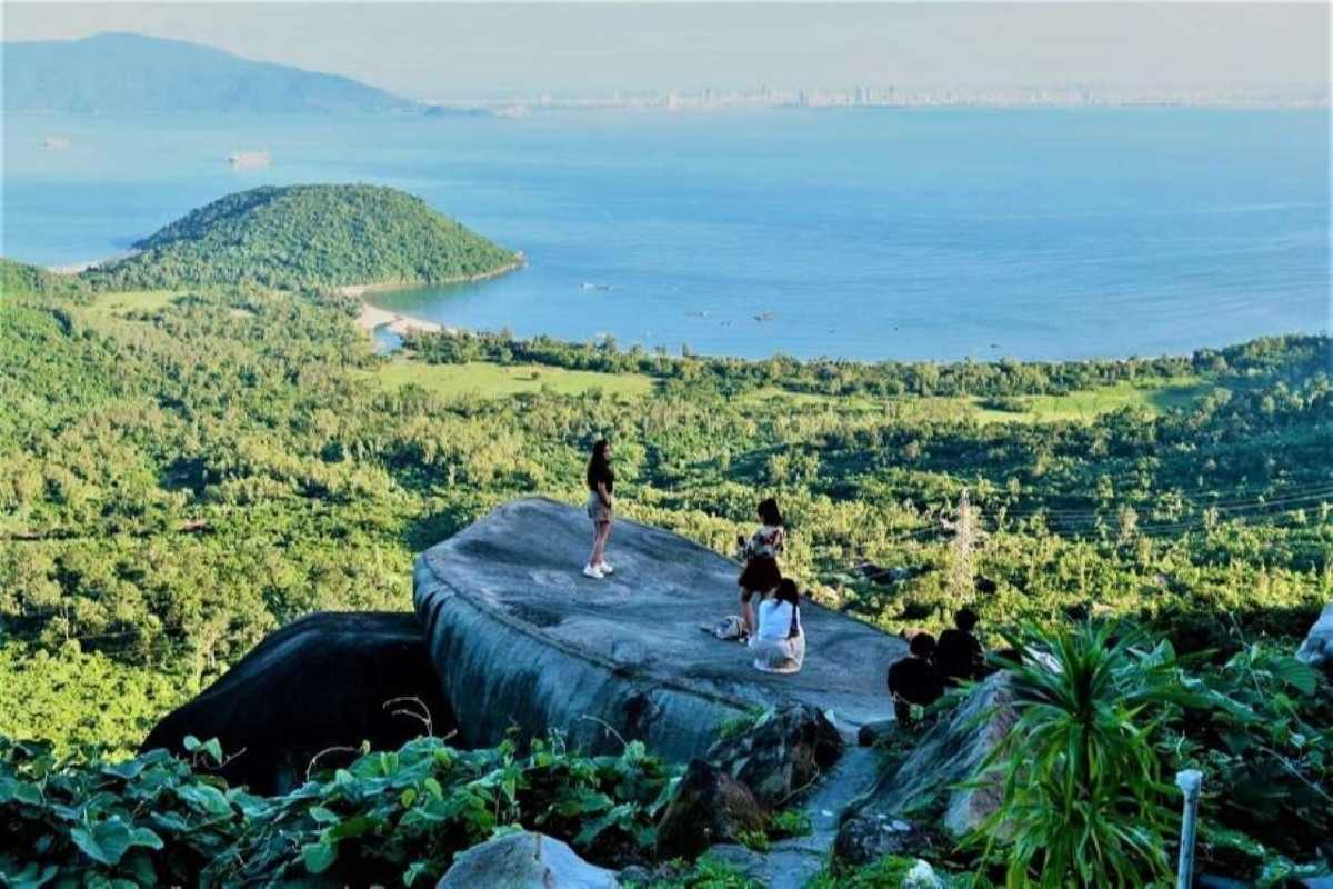 Hai Van Pass Vietnam panoramic rock lookout blue sea Hai Van Pass Vietnam panoramic rock lookout with visitors, lush hills, and brilliant blue sea under a sunny sky.