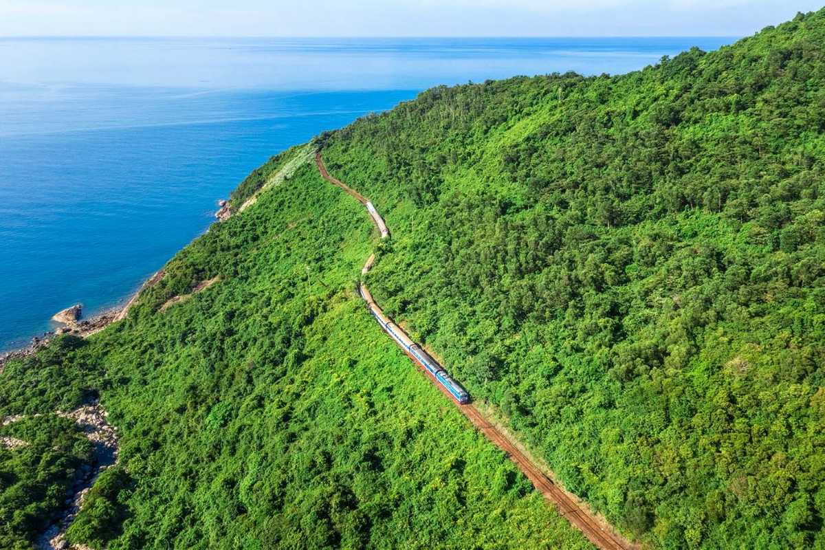 Hai Van Pass Vietnam railway coastline green hills Hai Van Pass Vietnam railway follows the lush coastline, train curving through green hills above the sea.