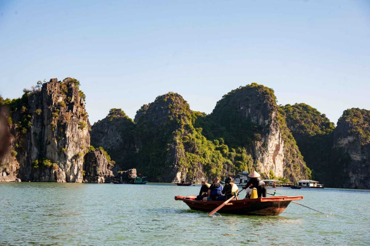 Halong Bay Landscape from Bamboo Boat Group of travelers enjoy bamboo boat ride with panoramic views of Halong Bay's rocky islets and emerald water at Ba Hang.