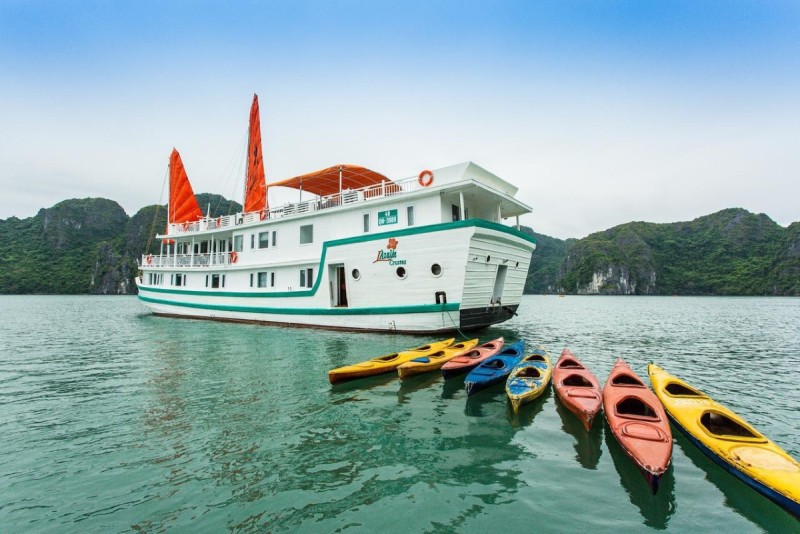 A white cruise boat docked in Halong Bay with colorful kayaks in the foreground, ready for an adventure near Titov Island.