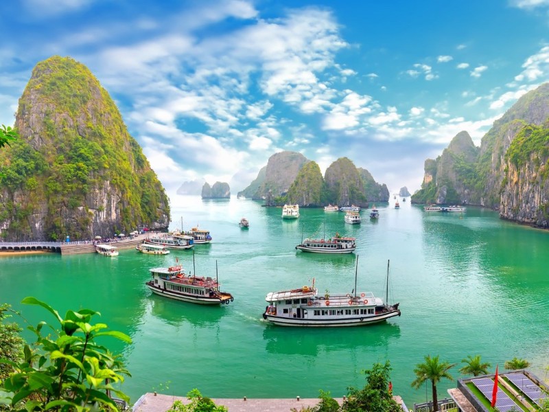 Halong Bay cruise with boats sailing among towering limestone mountains, capturing the natural beauty of the bay.