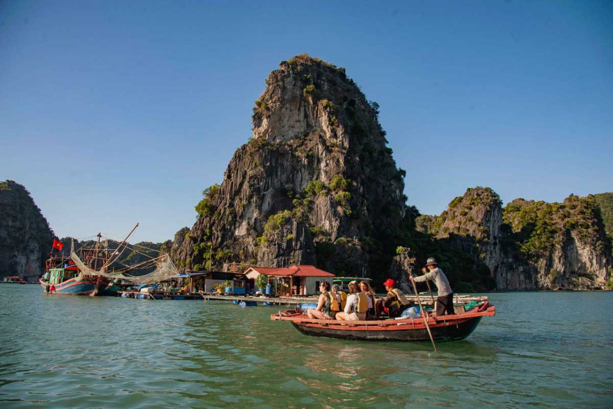 Exploring Limestone Karsts by Bamboo Boat Travelers cruise past towering limestone formations on bamboo boats near Ba Hang Fishing Village under clear skies in Halong Bay.
