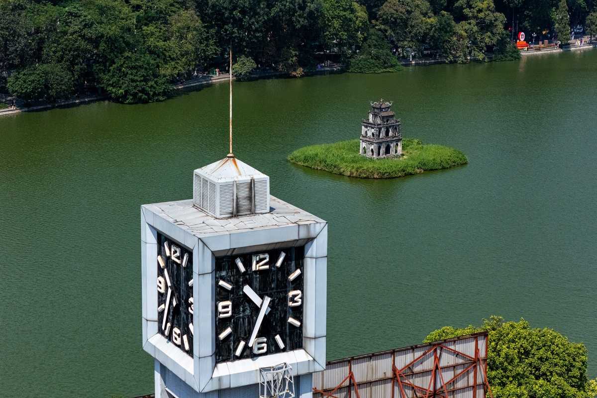 Hanoi Clock Tower with Turtle Tower in Background Hanoi city clock tower with Turtle Tower visible across Hoan Kiem Lake