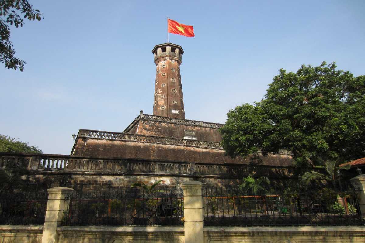 Hanoi Flag Tower from Tree-Lined Street Hanoi Flag Tower visible through leafy trees along a busy street
