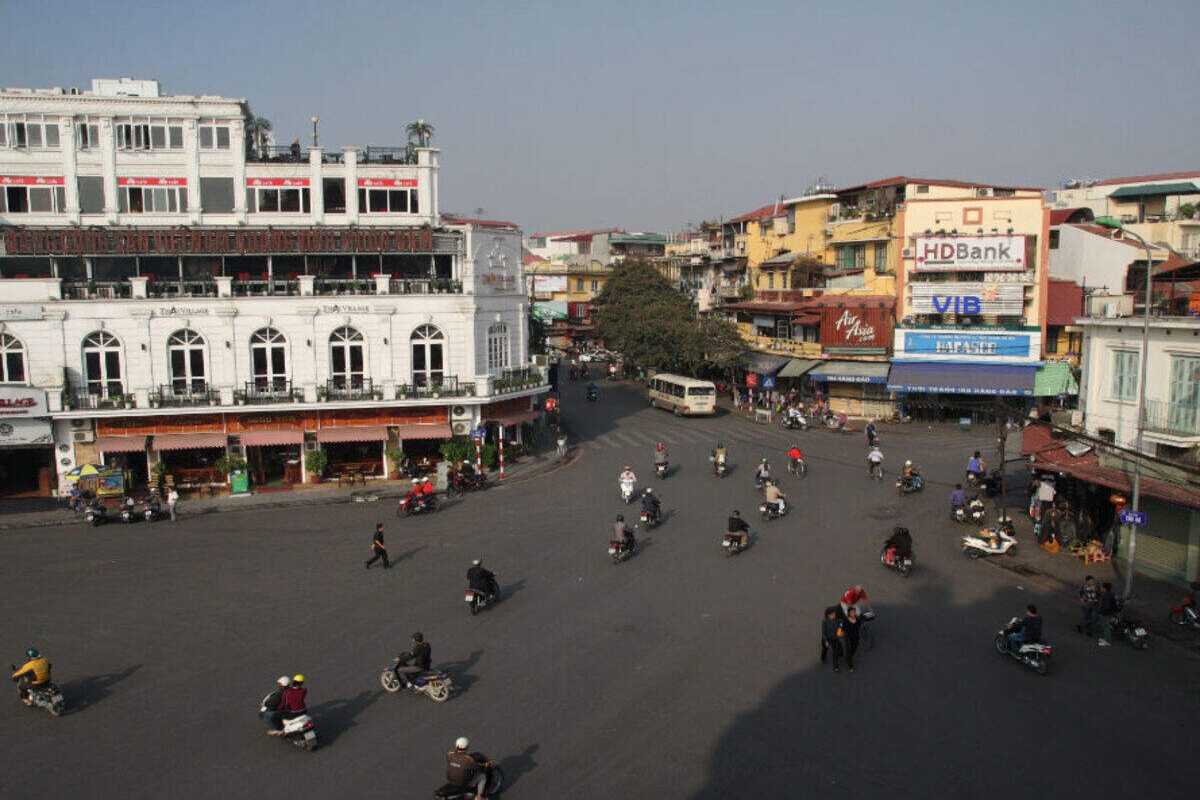 Hanoi Old Quarter street with motorbike traffic Busy intersection with motorbike traffic and historic buildings in the Hanoi Old Quarter