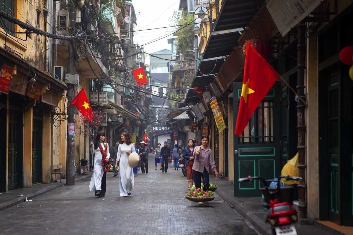 Hanoi Old Quarter Traditional Street Scene Traditional street scene in the Hanoi Old Quarter with locals walking and Vietnamese flags
