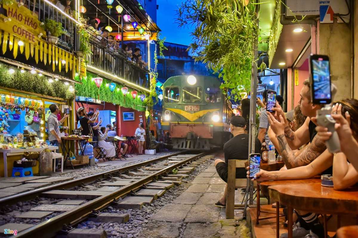 Nighttime Train Approaching on Hanoi Train Street Night photo of a train approaching with people seated beside Hanoi Train Street