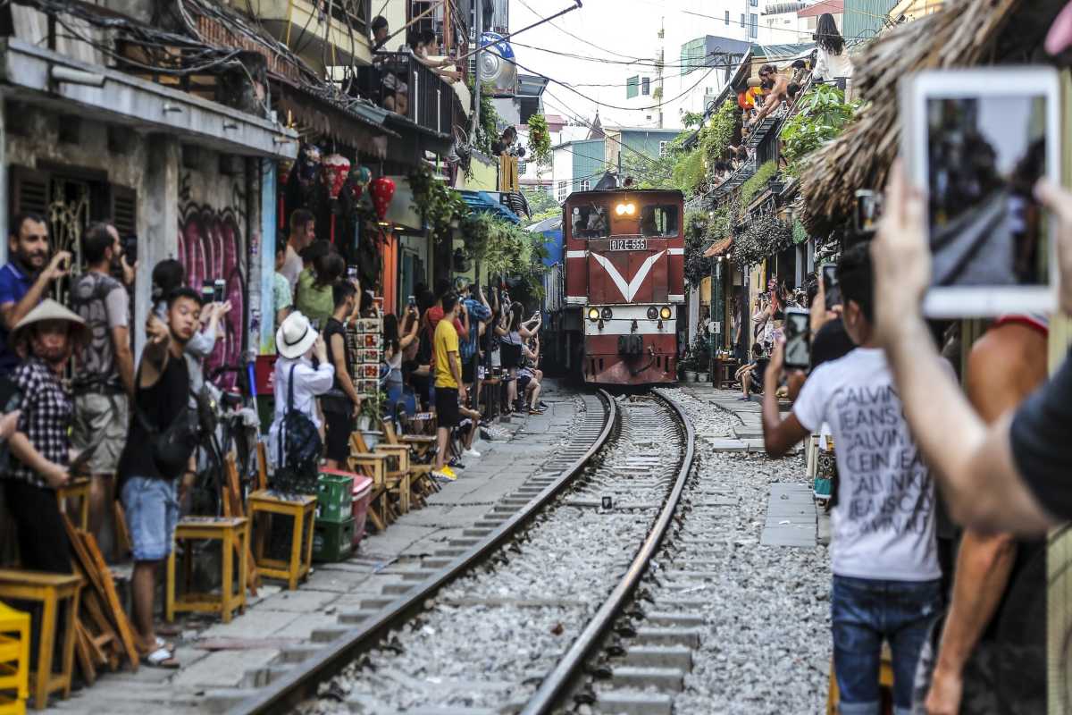 Train Passing Through Crowded Hanoi Train Street A train moving through Hanoi Train Street with crowds gathered on balconies and sidewalks