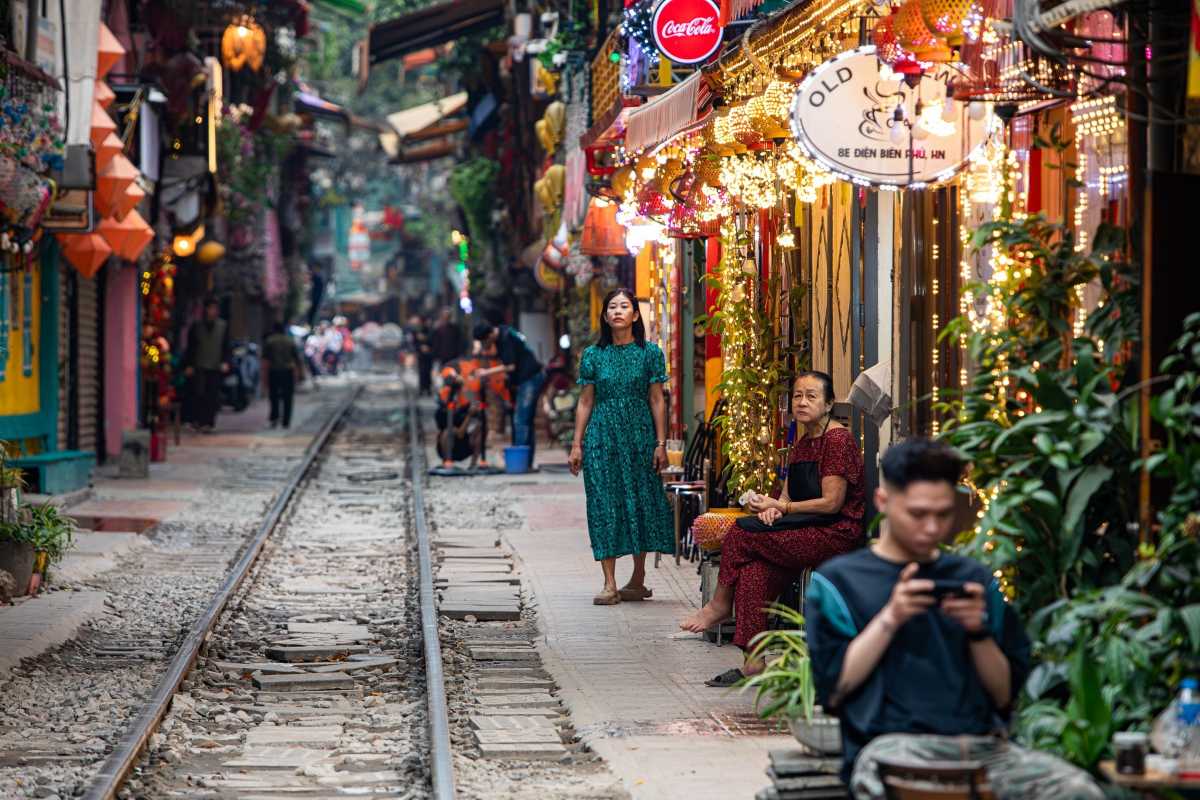 Tourists Walking and Sitting Along Hanoi Train Street Visitors walking and sitting near railway tracks on Hanoi Train Street