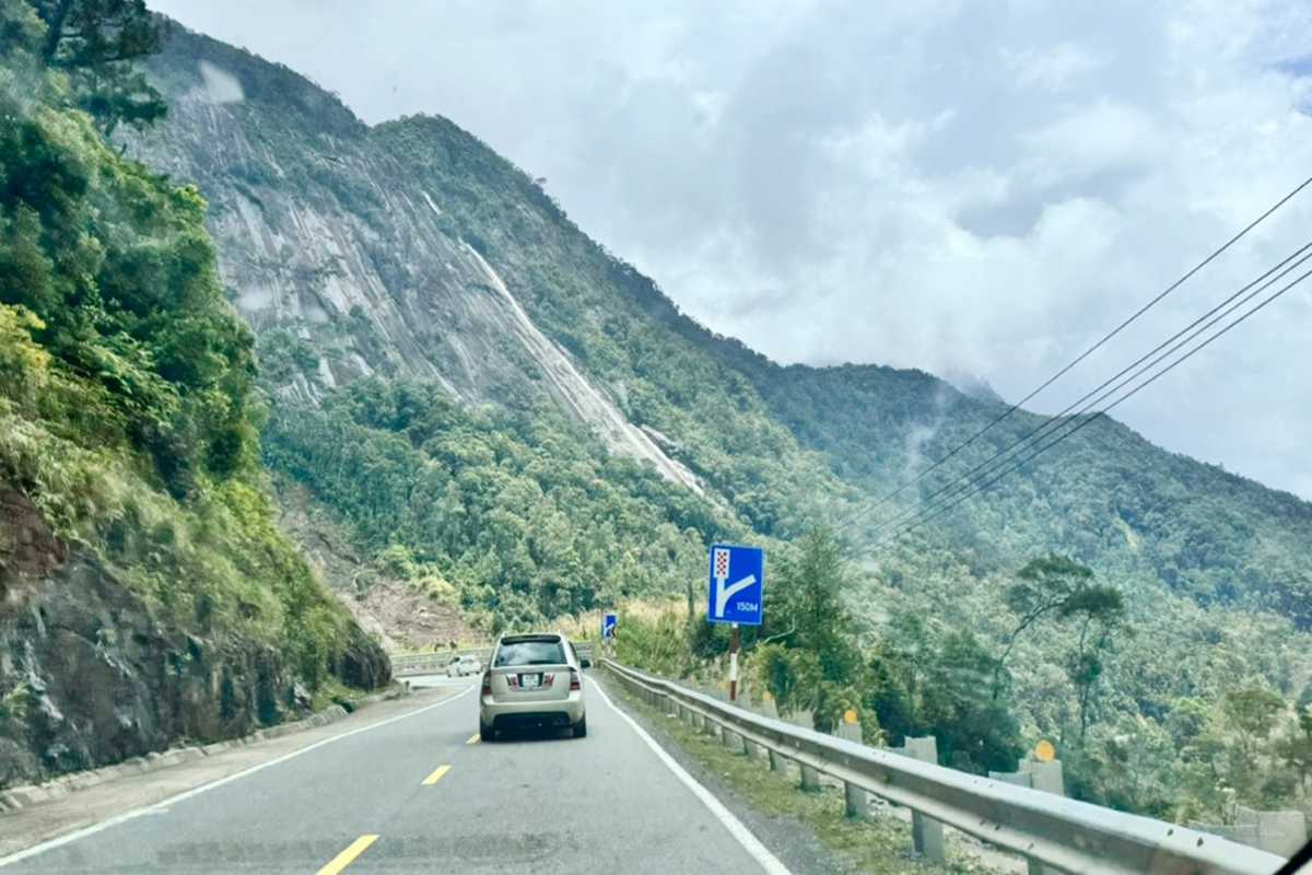 Mountain driving on scenic Heaven Pass Cars navigating mountain road with towering cliffs on Heaven Pass scenic highway.