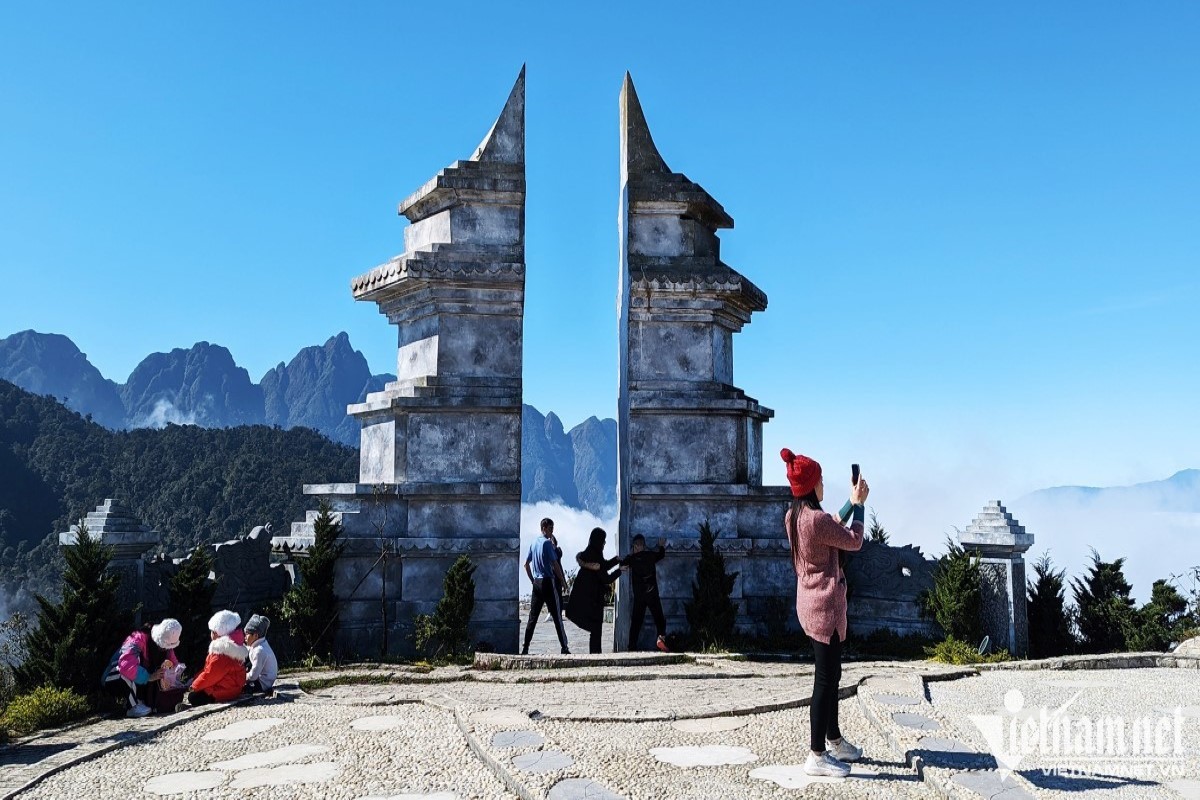 Scenic view of Heaven's Gate Sapa stone arch with visitors taking photos against the mountain backdrop.