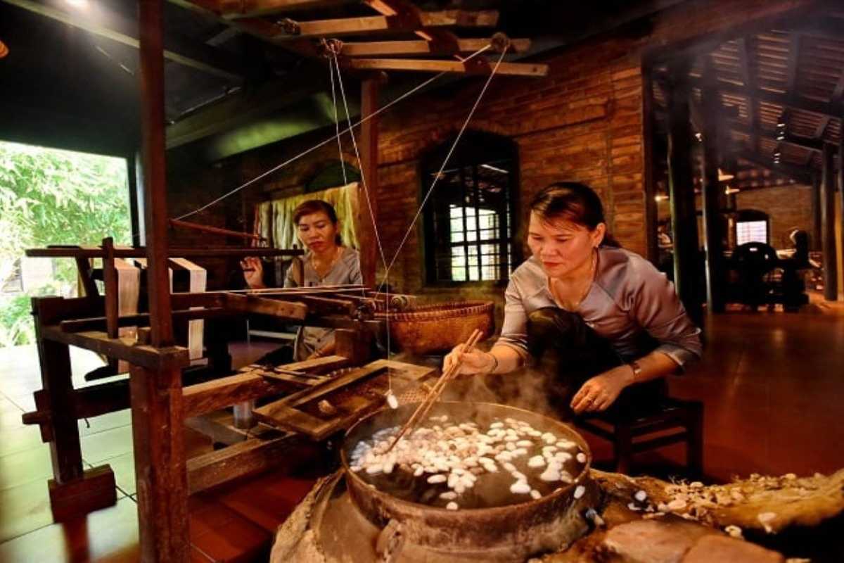 Boiling Silkworm Cocoons for Silk Extraction Artisan boiling white silkworm cocoons in a pot to extract silk threads inside Hoi An Silk Village