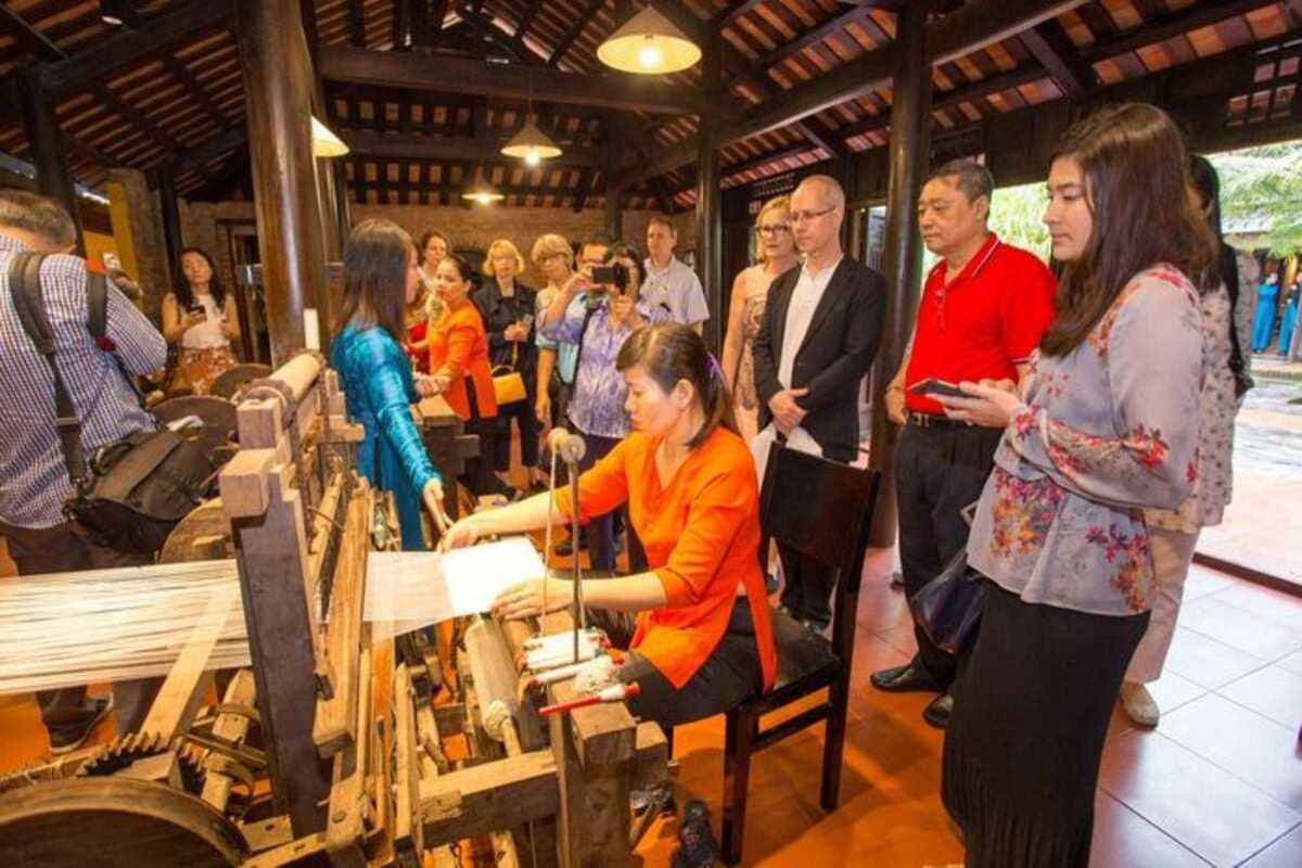 Tourists Watching Silk Weaving at Hoi An Silk Village Group of tourists observing a weaver operating a traditional loom at Hoi An Silk Village