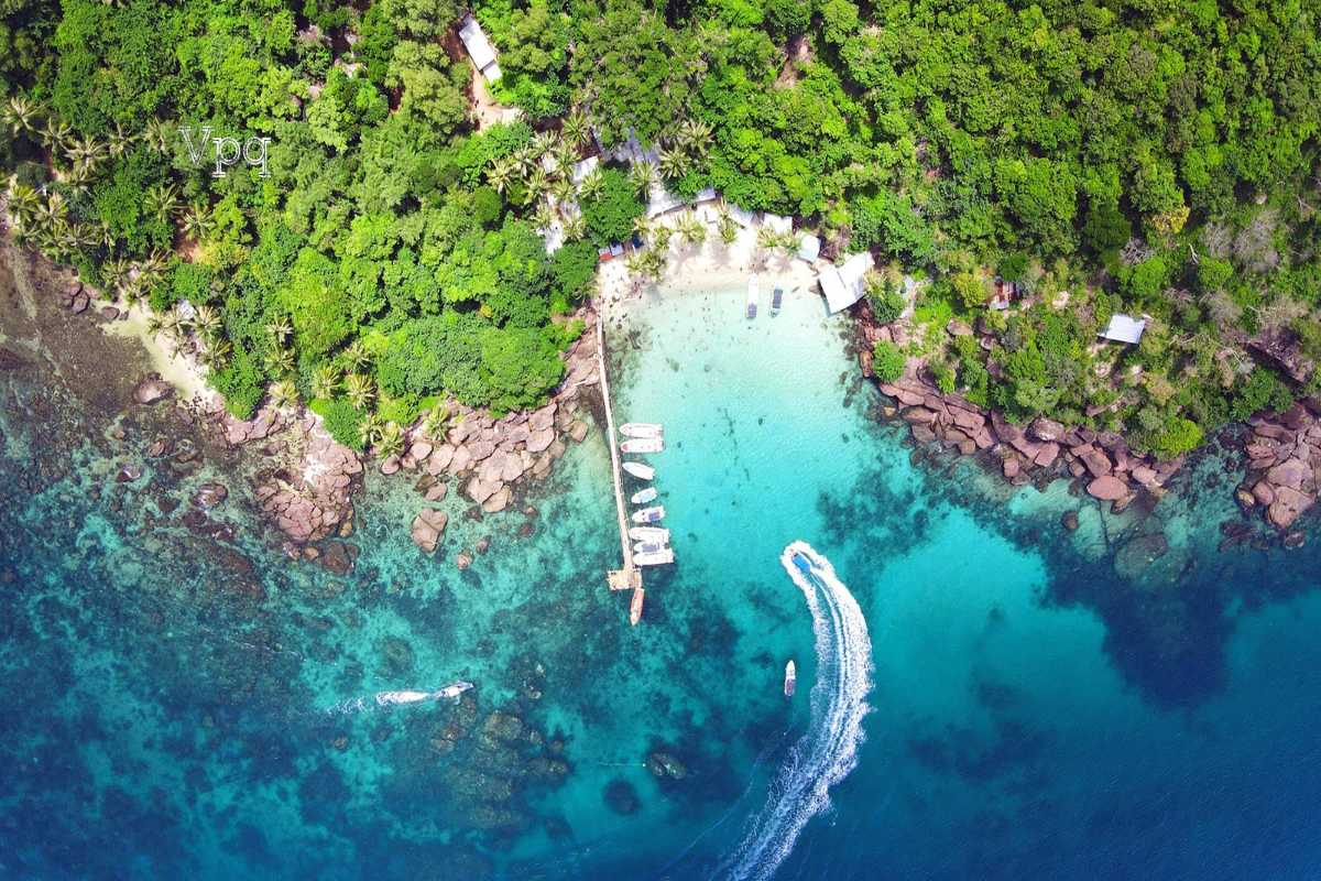 Hon Buom Island Phu Quoc Aerial Beach and Boats Aerial shot of boats docked at Hon Buom Island beach with clear shallow waters and palm trees.