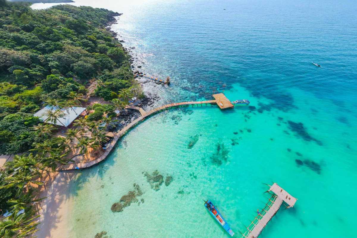Hon Buom Island Phu Quoc Beachfront Pier Aerial view of Hon Buom Island’s beachfront pier with boats docked and clear shallow water.