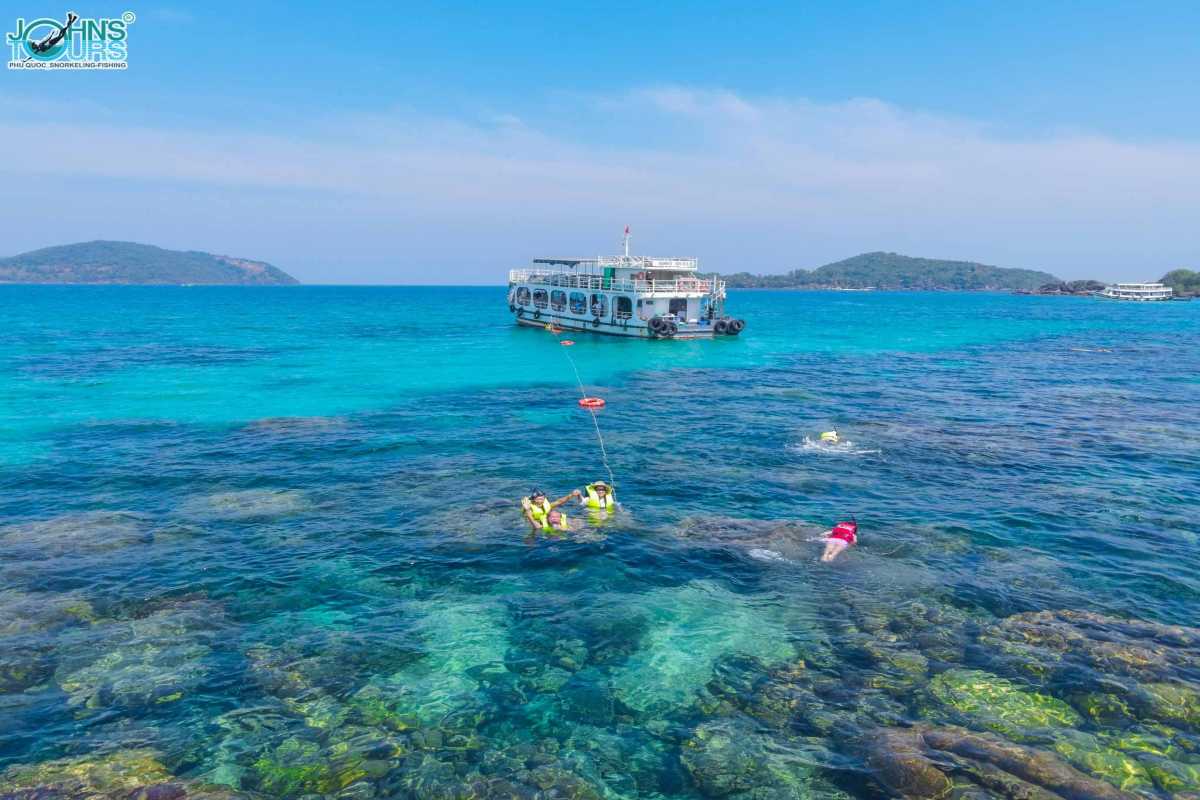 Hon Buom Island Phu Quoc Snorkeling Experience Tourists snorkeling over coral reefs near Hon Buom Island with clear water and colorful marine life.