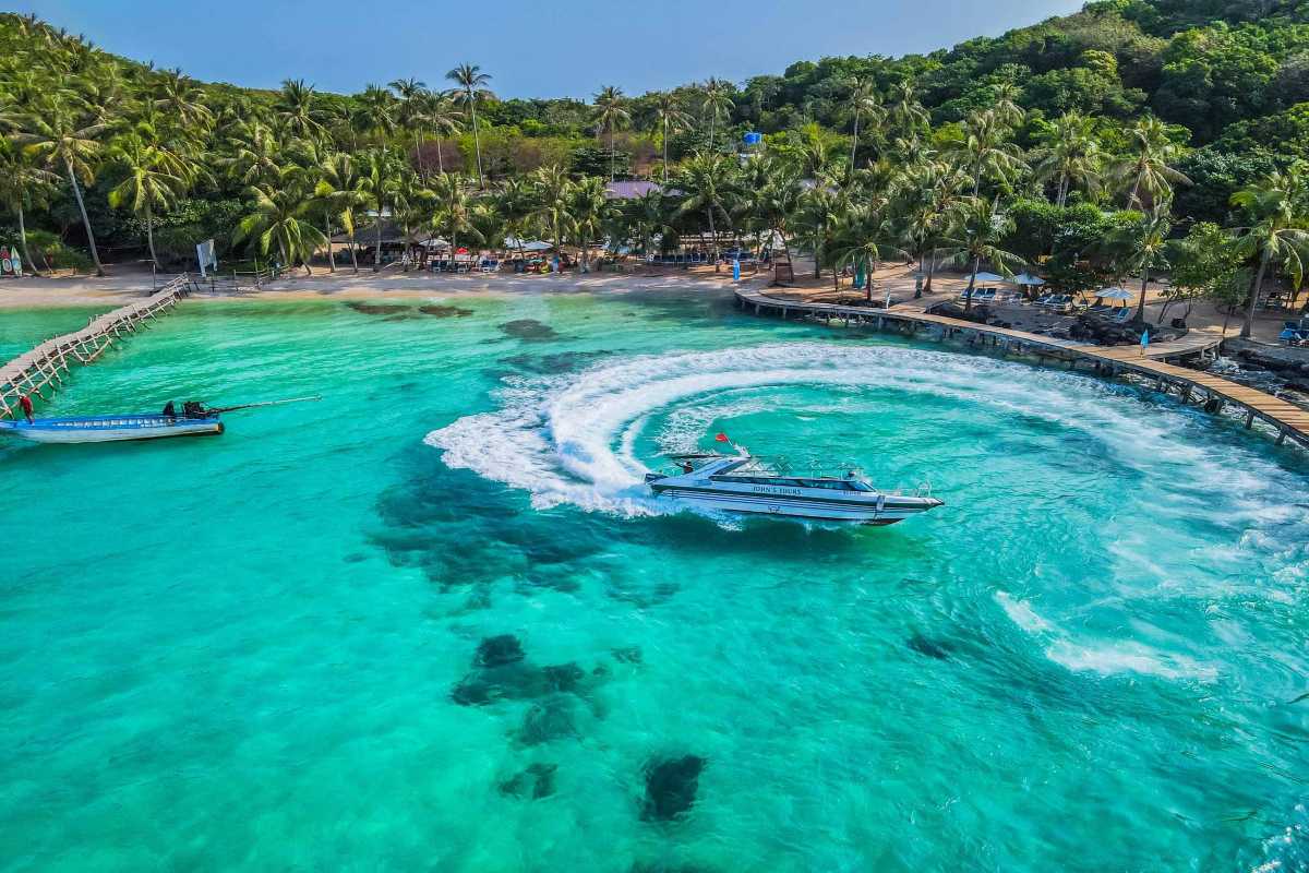 Hon Buom Island Phu Quoc Speedboat Adventure Speedboat creating waves near Hon Buom Island with palm-lined beaches and turquoise water.