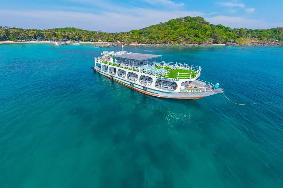 Hon Buom Island Phu Quoc Tour Boat White tour boat anchored near Hon Buom Island surrounded by calm blue waters in Phu Quoc.
