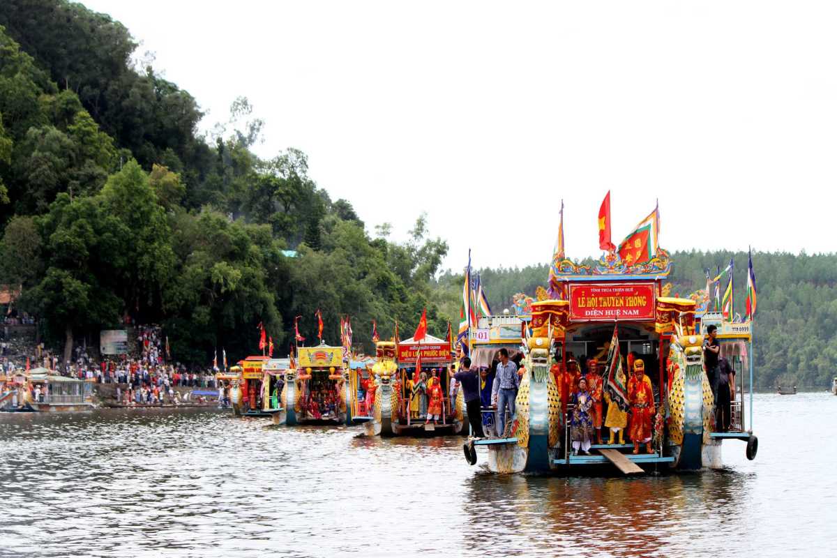 Hon Chen Temple Hue dragon boat parade Perfume River tradition Hon Chen Temple Hue traditional dragon boat parade with people in ceremonial dress along the river