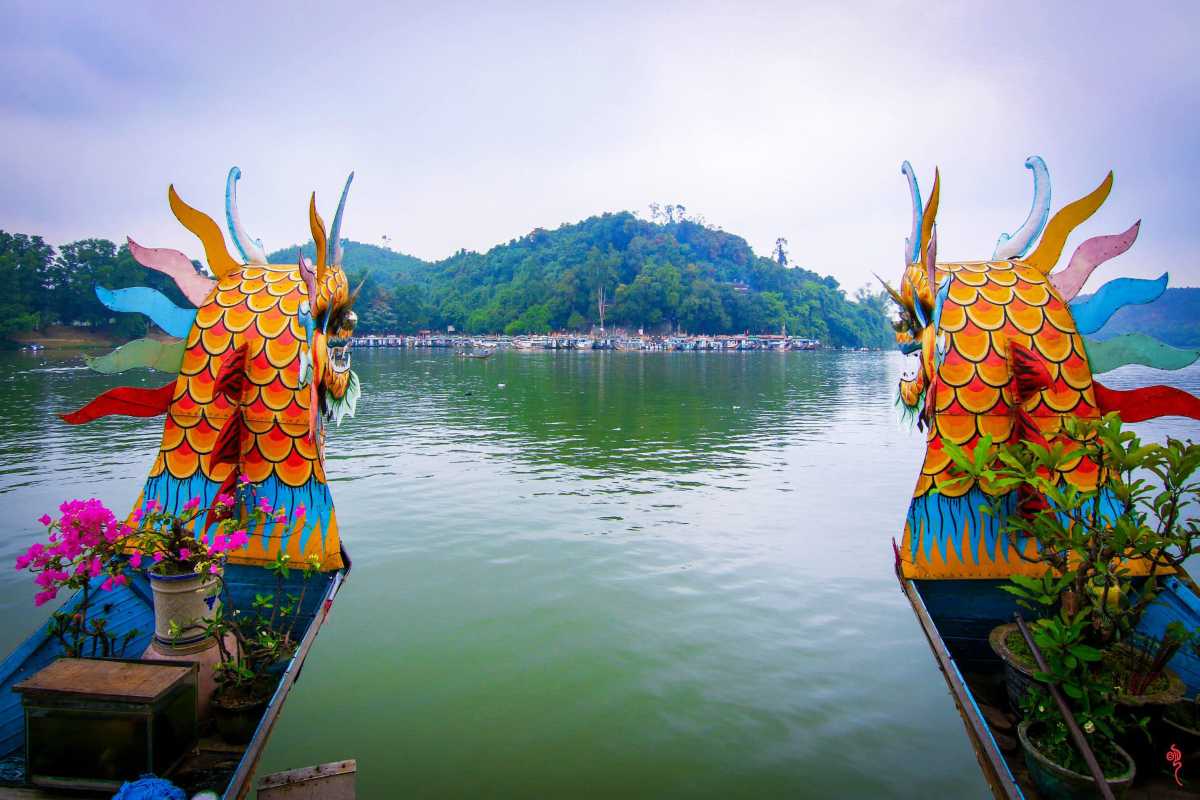 Hon Chen Temple Hue dragon boat river approach panoramic view Hon Chen Temple Hue colorful dragon boats facing the river with Ngoc Tran Mountain in the background
