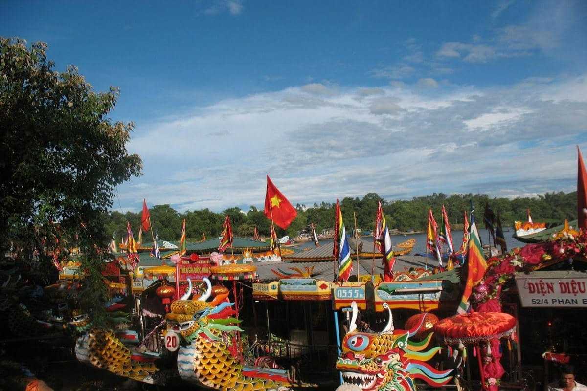 Hon Chen Temple Hue vibrant dragon boats Perfume River festival scene Hon Chen Temple Hue dragon boats decorated with flags and vibrant colors on Perfume River during festival