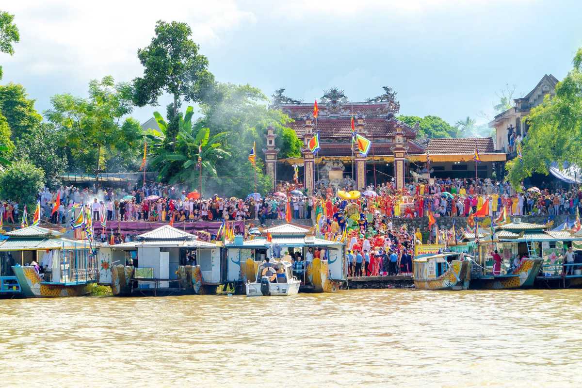 Hon Chen Temple Hue festive crowds riverside entrance celebration Hon Chen Temple Hue main entrance crowded with visitors and colorful flags during a vibrant festival