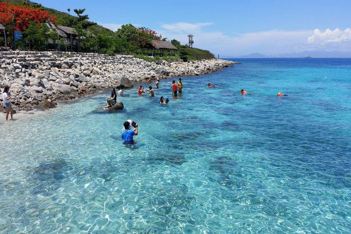 Tourists enjoying shallow snorkeling at Hon Mun People playing and snorkeling in clear shallow waters near Hon Mun Island’s rocky shoreline.