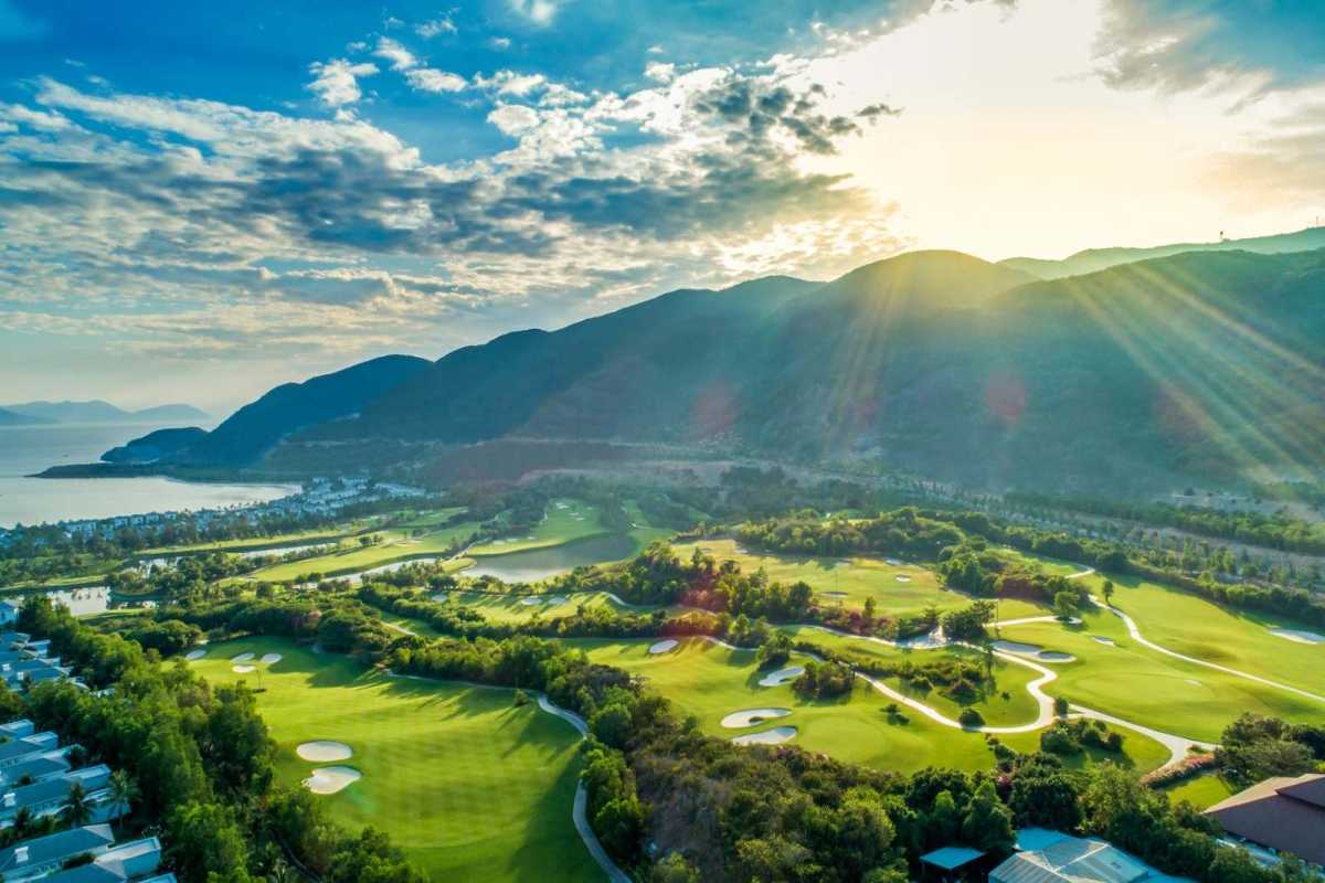 Scenic view of golf course and resort on Hon Tre Island with mountains and sunlight in background