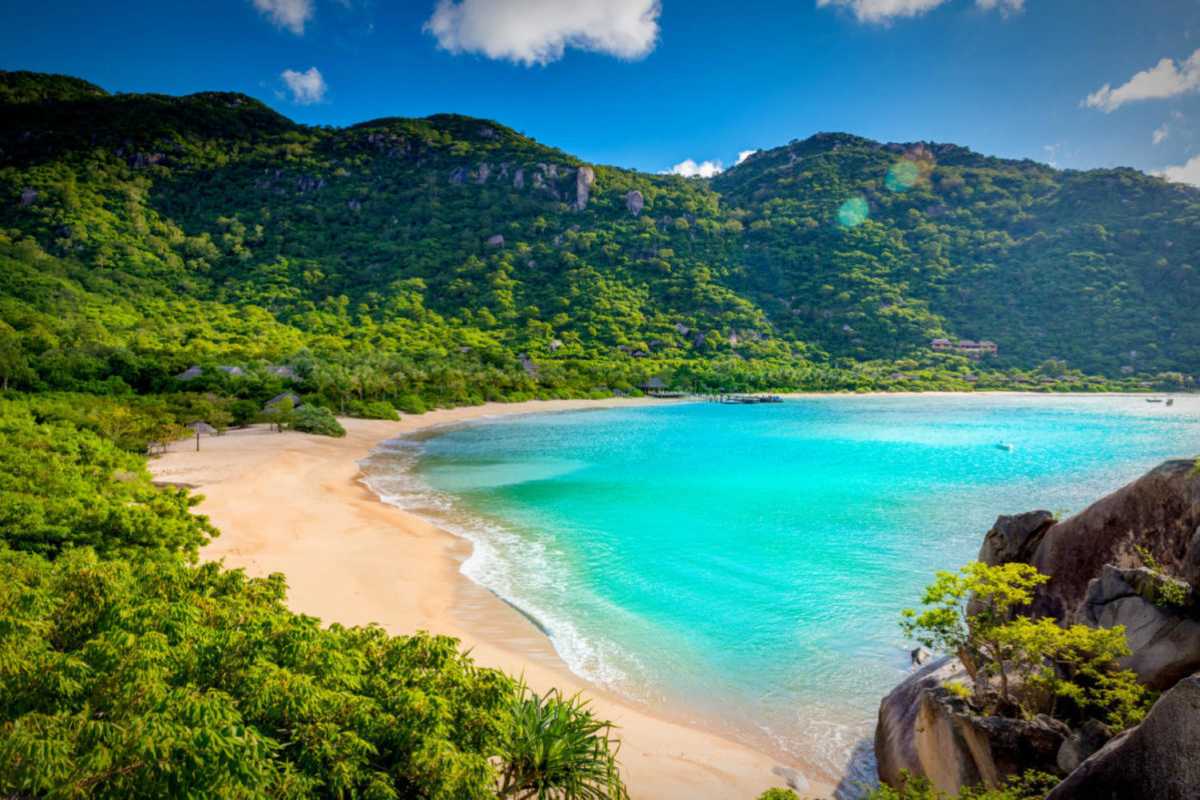 Pristine Beach on Hon Tre Island White sand beach on Hon Tre Island surrounded by tropical green hills and turquoise water