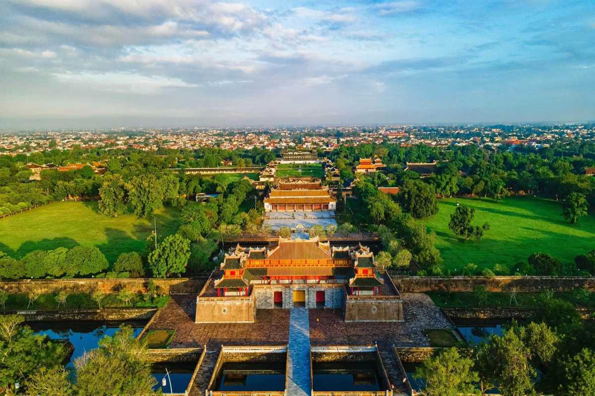 Lush gardens and palaces of Hue Imperial City in morning Hue Imperial City stretches toward the horizon with lush gardens, ornate palaces, and ancient gates under a clear blue sky in Hue.