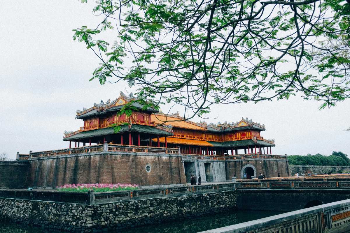 Ngo Mon Gate and lotus moat at Hue Imperial City The impressive Ngo Mon Gate of Hue Imperial City rises above the lotus-filled moat, framed by tree branches and historic stone walls.