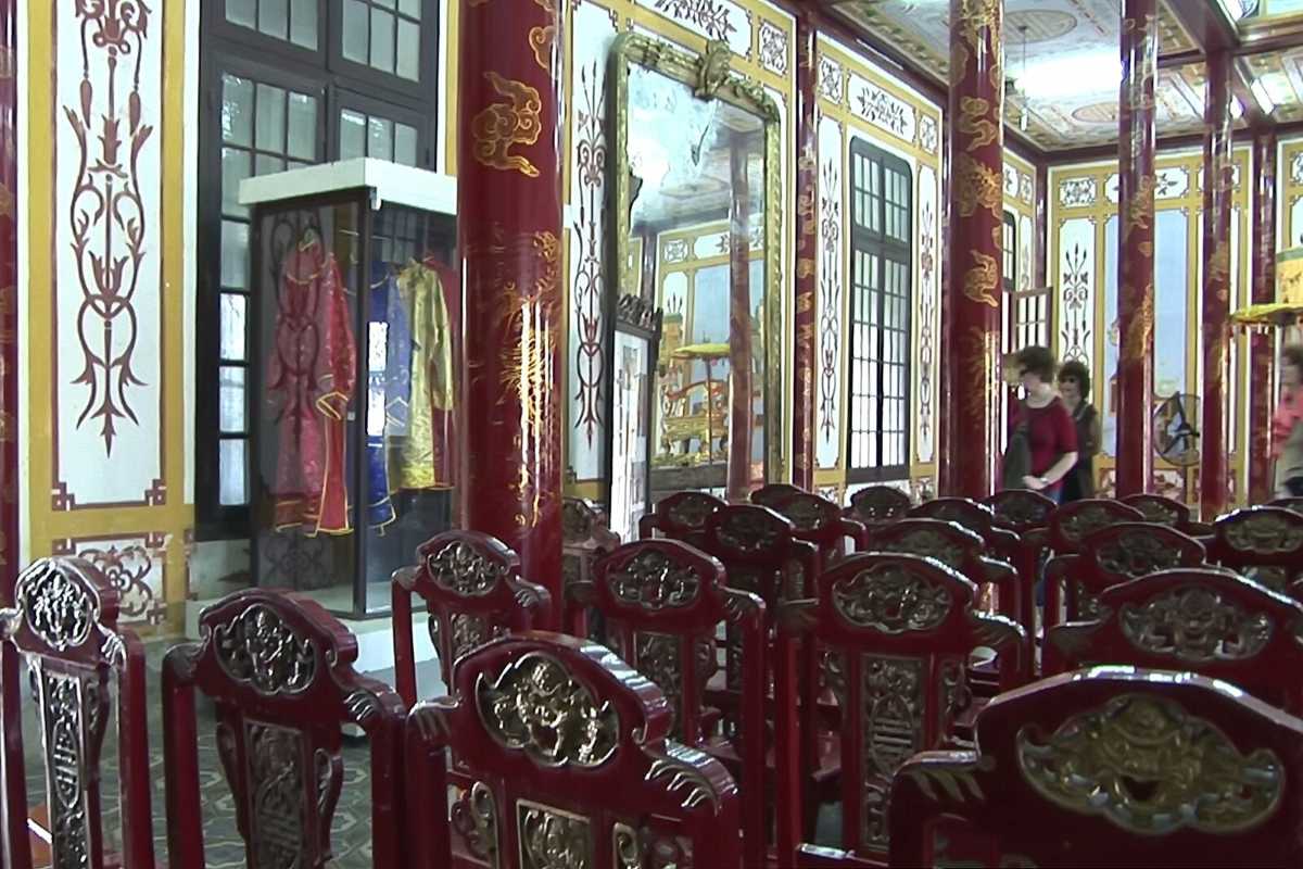 Exhibition room with royal costumes at Hue Museum of Royal Antiquities Exhibition room featuring Nguyen Dynasty royal costumes and ornate red columns at Hue Museum of Royal Antiquities