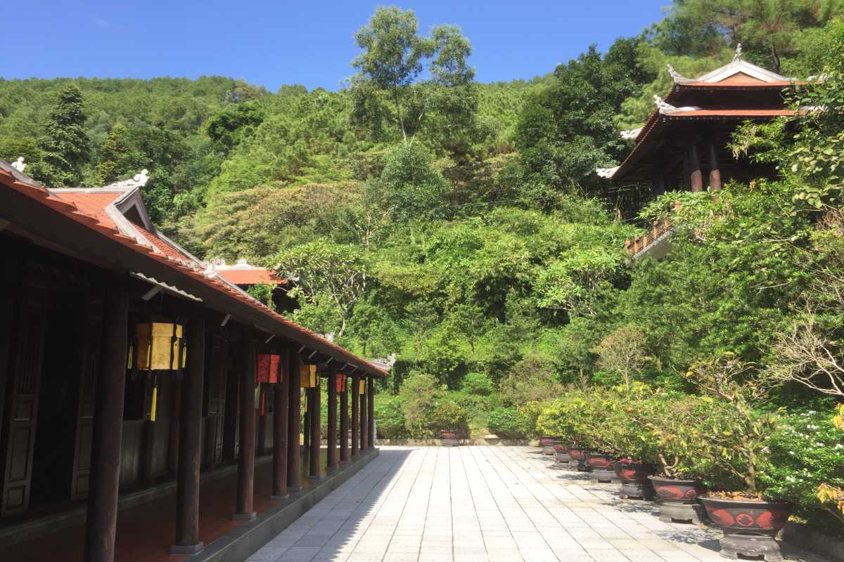 Huyen Khong Son Thuong Pagoda Hue main hall with lush green mountain view Huyen Khong Son Thuong Pagoda Hue main hall set against vibrant green mountain backdrop, traditional columns, and open walkway
