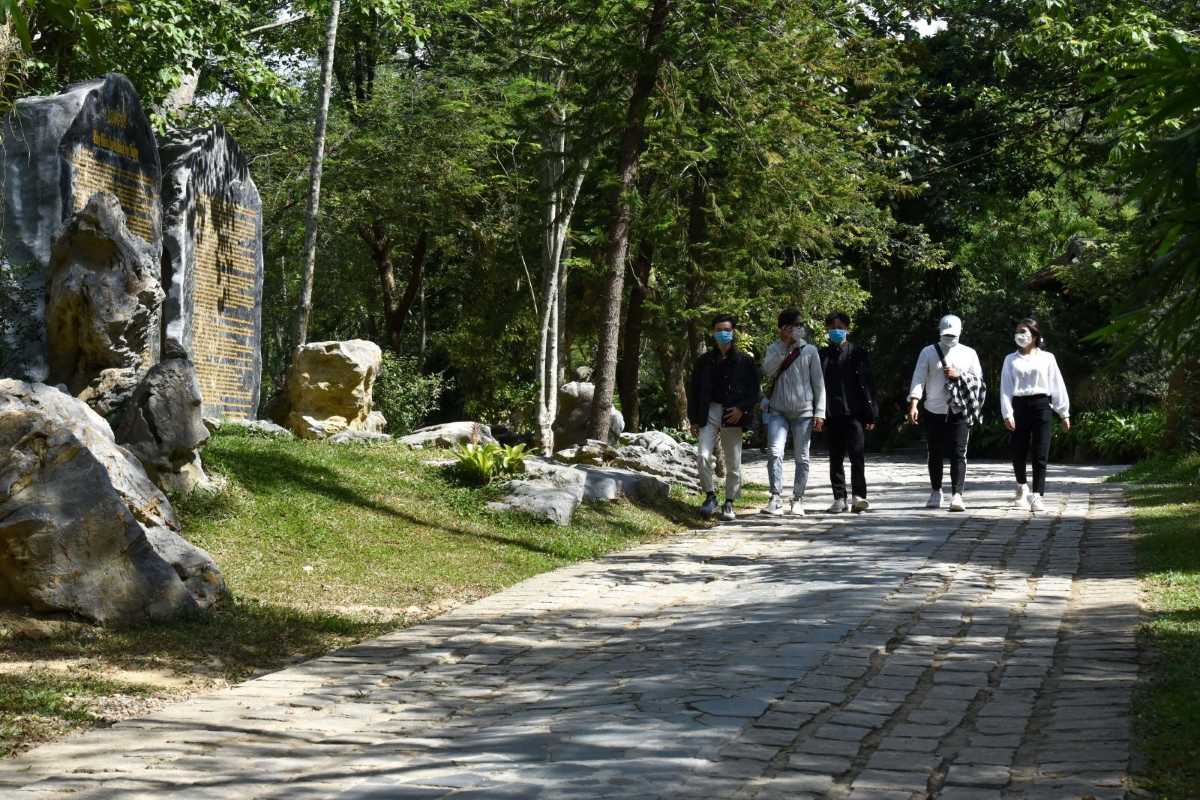 Huyen Khong Son Thuong Pagoda Hue shaded walkway with stone tablets and visitors Huyen Khong Son Thuong Pagoda Hue shaded walkway beside large stone tablets inscribed with history, visitors walking past, lush forest