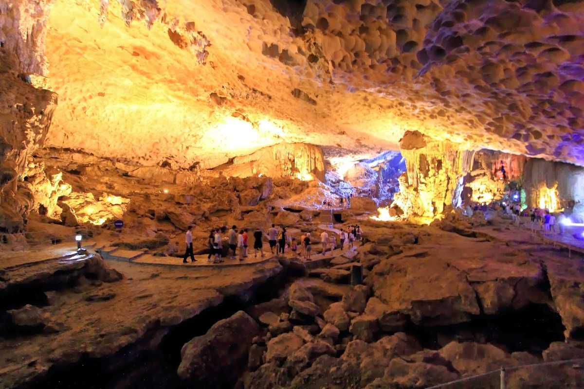 Illuminated interior of Sung Sot Cave Halong Bay Colorful illuminated rock formations inside Sung Sot Cave Halong Bay with tourists walking along the paved path
