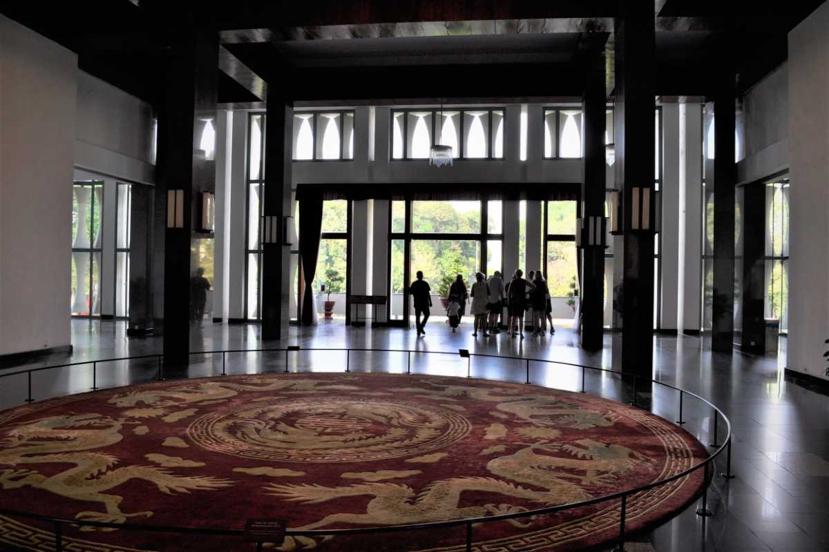 Independence Palace Saigon Main Hall Visitors Visitors exploring the main hall of Independence Palace Saigon with large circular carpet and pillars