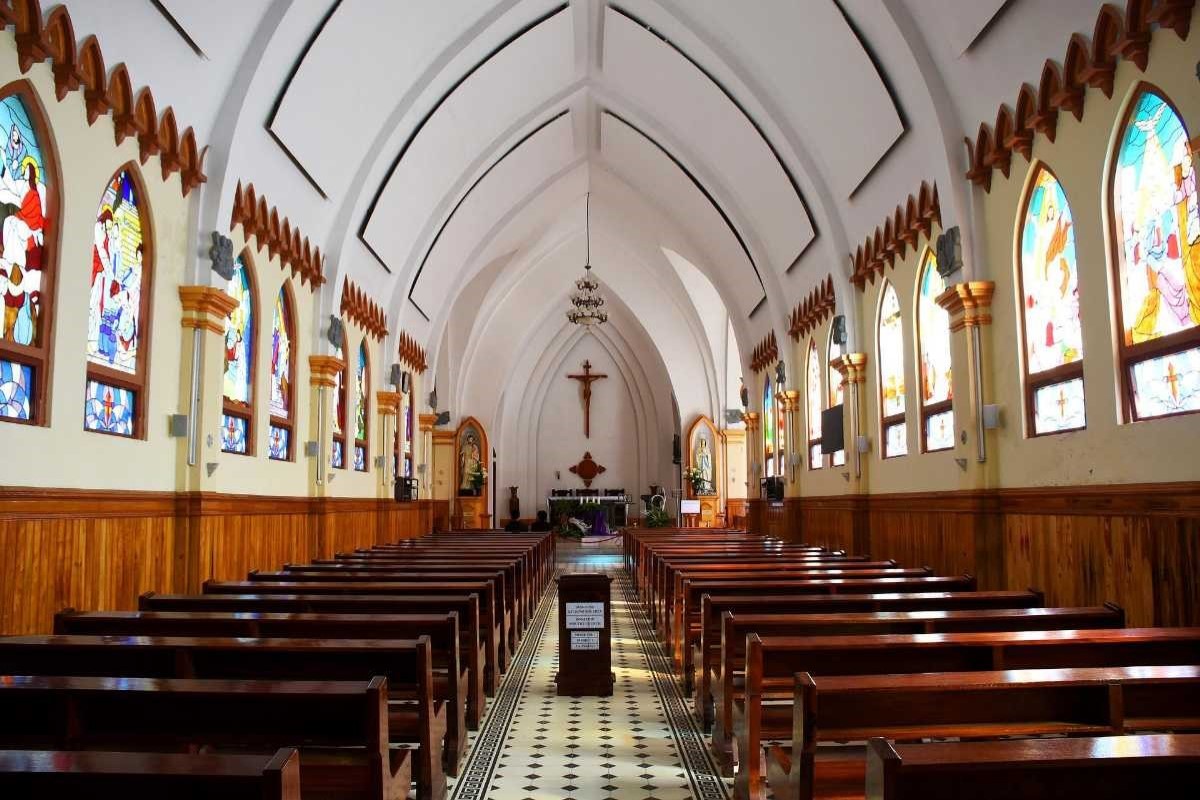 The beautiful interior of Sapa Stone Church, showcasing its Roman Gothic architecture, stained glass windows, and wooden benches.