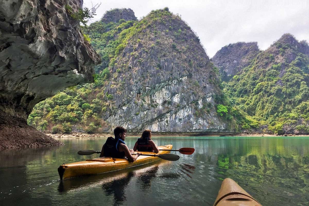 Kayaking in Ha Long Bay’s limestone caves surrounded by serene waters.