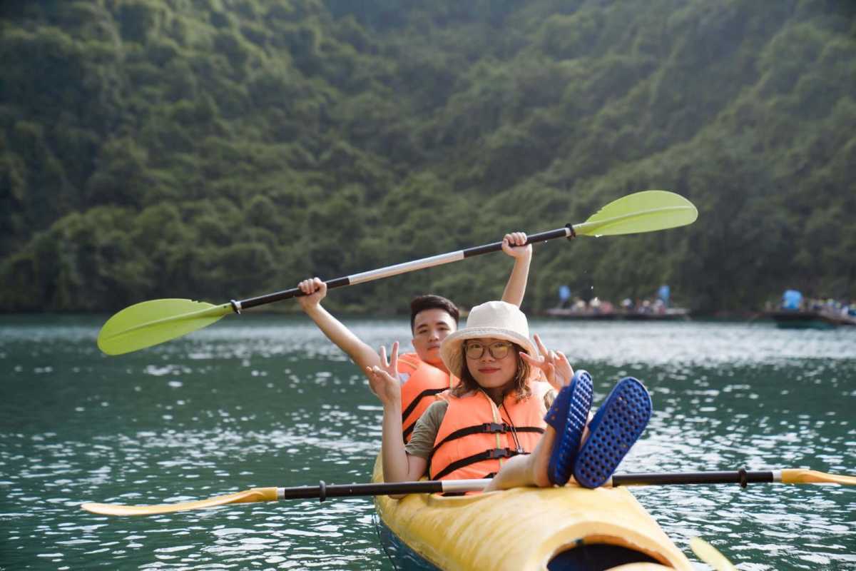 Kayaking Luon Cave Halong Bay calm emerald waters Kayakers paddle through the calm emerald waters of Luon Cave Halong Bay surrounded by limestone cliffs