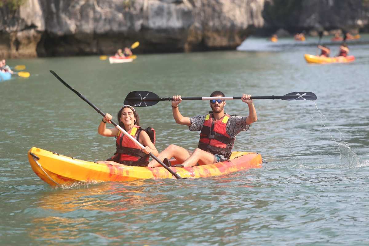 Kayaking Luon Cave Halong Bay lush green paddling Kayakers paddling amidst lush green vegetation and limestone cliffs in Luon Cave Halong Bay