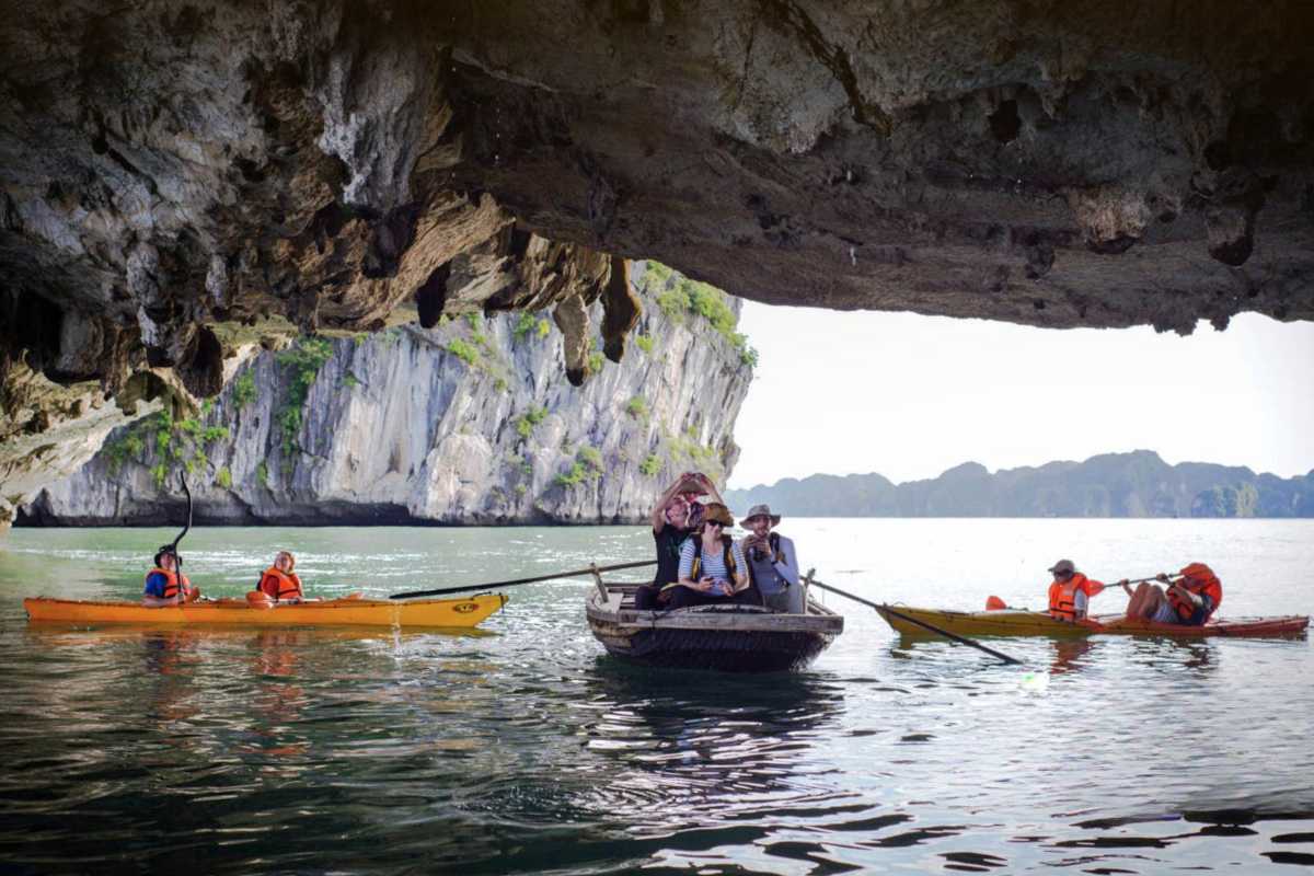 Kayaking Luon Cave Halong Bay paddling under cave roof Kayakers maneuvering beneath the rocky ceiling of Luon Cave inside Halong Bay