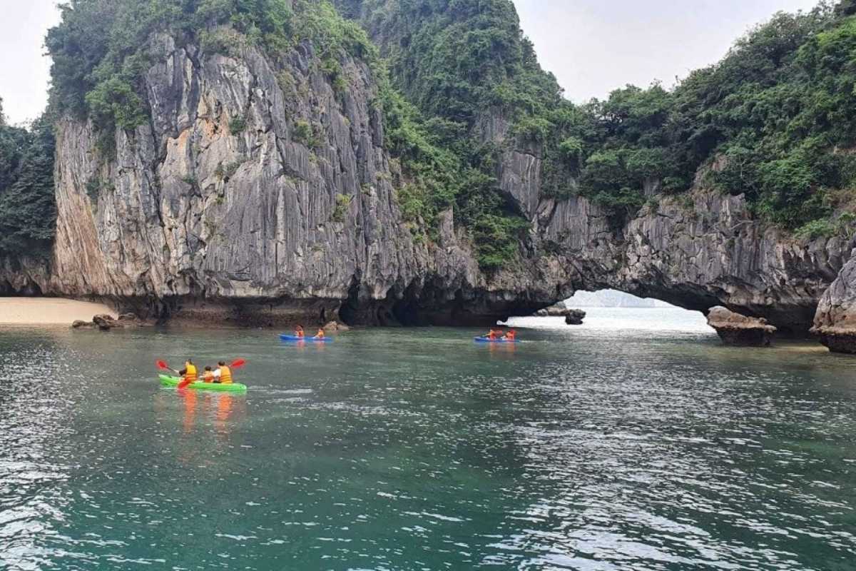 Kayaking Luon Cave Halong Bay scenic water passage Kayaking Luon Cave Halong Bay showcasing colorful kayaks navigating through a scenic water passage beneath limestone cliffs