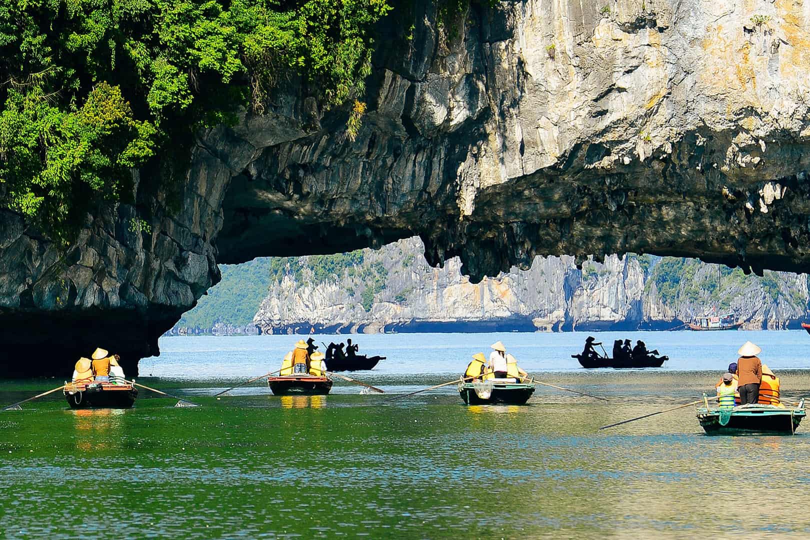 Kayakers exploring Luon Cave's tranquil lagoon, surrounded by towering limestone cliffs in Ha Long Bay.