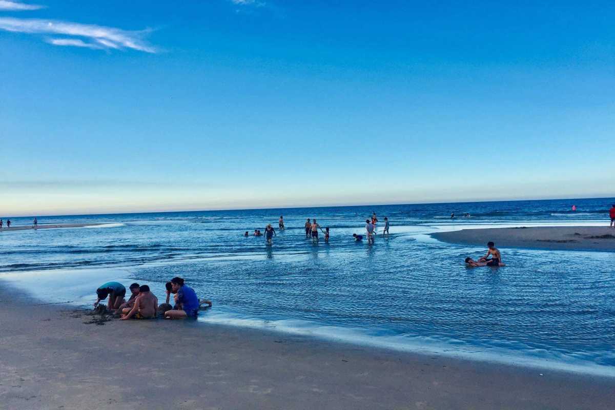 Lang Co Beach Hue families swimming in shallow blue water Lang Co Beach Hue shows families and children enjoying safe, shallow waters and soft sandy beach, perfect for fun and relaxation.